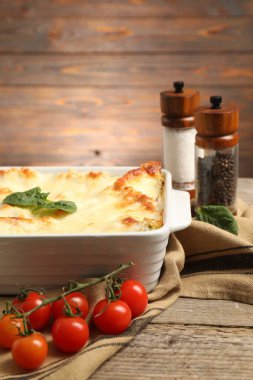 Pişirme kabında ıspanaklı lazanya ve ahşap masada malzemeler.