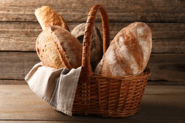 Tahta masadaki hasır sepette farklı somunlar.