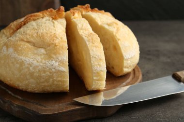 Koyu dokulu masada taze ekmek ve bıçak dilimleri, yakın plan.