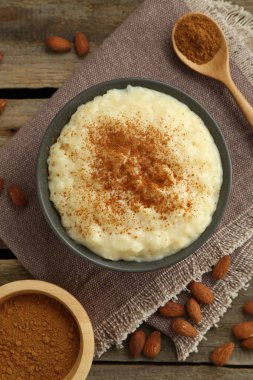 Tarçınlı lezzetli sütlaç ve ahşap masada badem.
