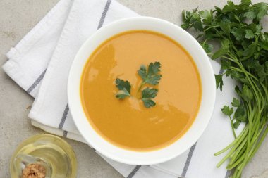 Maydanozlu mercimek kremalı çorba ve açık gri masada yağlı, düz uzanmış.