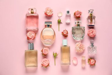 Parfüm şişeleri ve pembe arka planda güzel çiçekler.