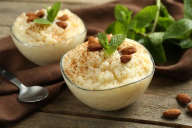 Tarçınlı lezzetli sütlaç, badem ve nane, ahşap masada servis edilir, yakın plan.