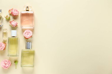 Parfüm şişeleri ve bej arka planda güzel çiçekler. Metin için boşluk