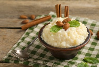 Tahta masada servis edilen bademli, nane ve tarçınlı lezzetli sütlaç, yakın plan.