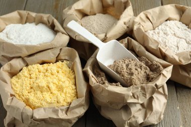 Tahta masadaki kağıt torbalarda farklı türde un, yakın plan.