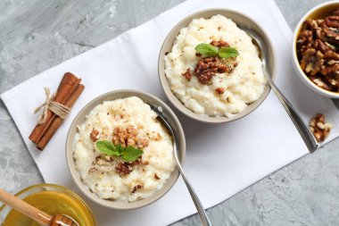 Cevizli, tarçınlı, nane ve ballı lezzetli sütlaç gri masada, düz yerde.