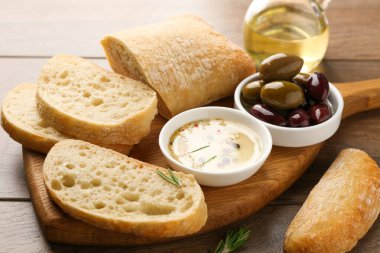 Ahşap masada yağlı, zeytinli ve baharatlı dilimlenmiş ekmek, yakın plan.