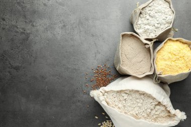 Gri masadaki poşetlerdeki farklı tipte un, düz. Metin için boşluk