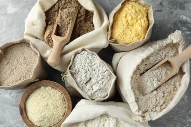 Gri desenli sehpada, düz yerde duran farklı tipte un var.