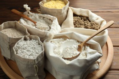 Tahta masadaki poşetlerdeki farklı un türleri, yakın plan.