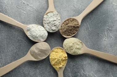 Gri masadaki kaşıklarda farklı türde un, düz.