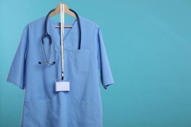 Steteskop ve rozeti mavi arka planda asılı sağlık görevlisi üniforması. Metin için boşluk