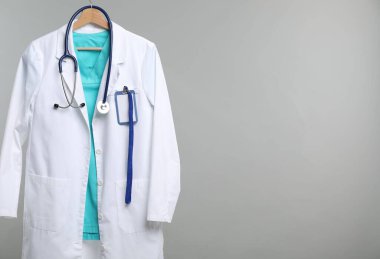 Üzerinde steteskop ve rozet olan doktor ceketi gri arka planda. Metin için boşluk