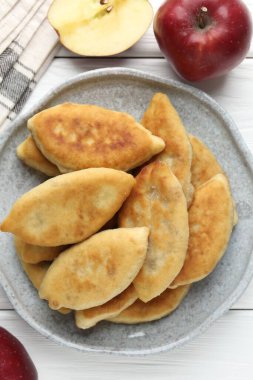 Lezzetli kızarmış pirizky (doldurulmuş turtalar) ve beyaz ahşap masa üzerinde elmalar, düz yatıyordu.
