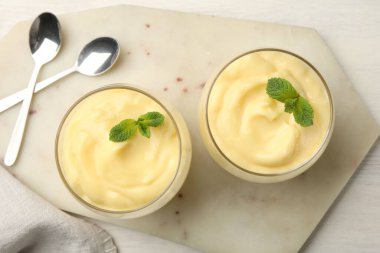Beyaz ahşap masada servis edilen nane aromalı vanilyalı puding.
