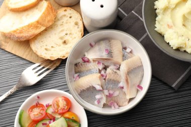 Siyah ahşap masada servis edilen soğanlı lezzetli ringa balıkları.