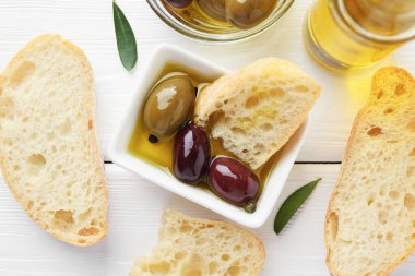 Beyaz ahşap masa üzerinde yağlı ve zeytinli dilimler, düz yatıyordu.