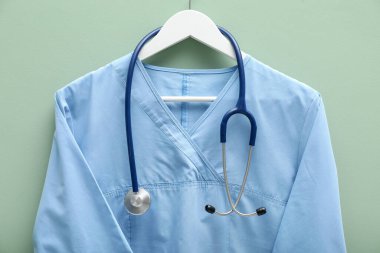 Açık mavi arka planda steteskoplu sağlık çalışanı üniforması.