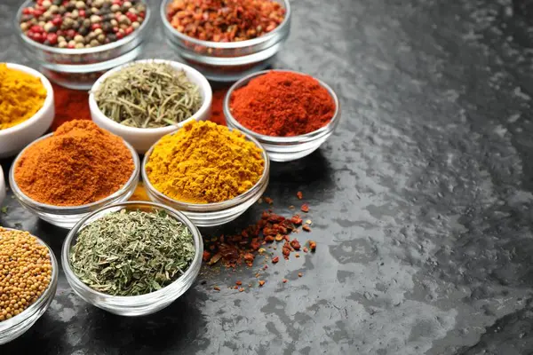 Karanlık masadaki kaselerde farklı aromatik baharatlar, yakın plan. Metin için boşluk