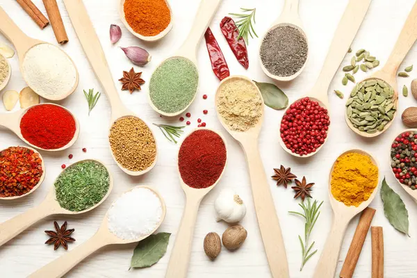 Beyaz ahşap masadaki kaşıklardaki farklı aromatik baharatlar.