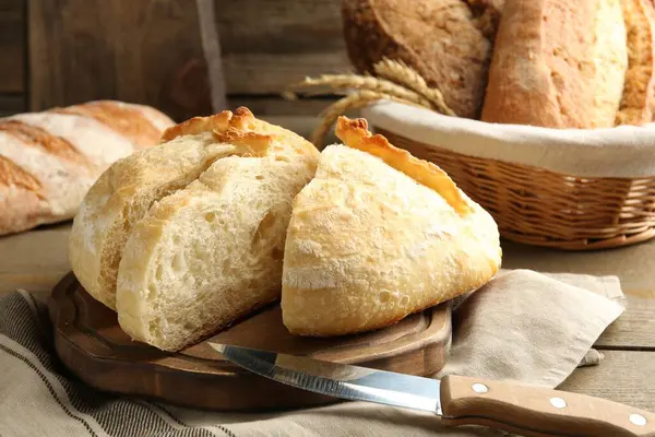 Farklı somunlar taze ekmek, bıçak ve çiviler ahşap masada, yakın plan
