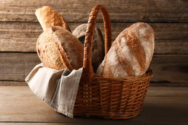 Tahta masadaki hasır sepette farklı somunlar.