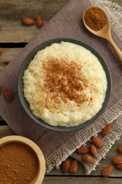 Tarçınlı lezzetli sütlaç ve ahşap masada badem.