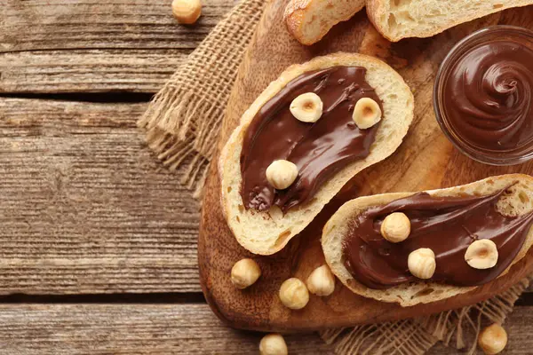 Çikolata sürülmüş ekmek dilimleri ve ahşap masada fındıklar, düz yatak. Metin için boşluk