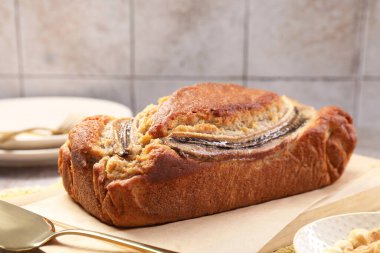 Ev yapımı muz ekmeği, servis elemanı ve fındıklar masada, yakın plan.