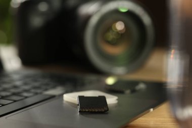 SD hafıza kartları, tutucu, dizüstü bilgisayar ve fotoğraf makinesi ahşap masada, yakın plan.