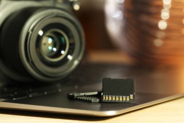 SD hafıza kartları, dizüstü bilgisayar ve fotoğraf makinesi masada, yakın plan.