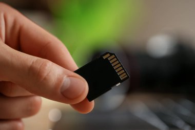 Bulanık arkaplanda SD hafıza kartı olan adam, yakın plan