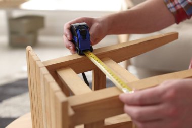 İçerideki bantla ahşap tabureyi ölçen adam, yakın plan.