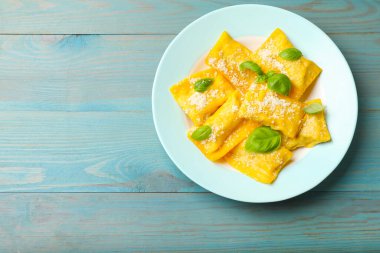 Açık mavi ahşap masada peynirli ve fesleğenli nefis ravioli, üst manzara. Metin için boşluk