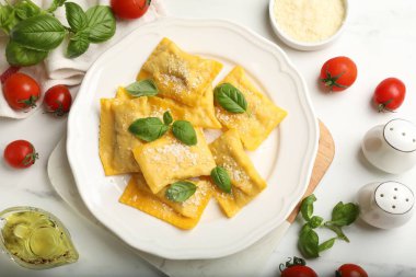 Beyaz mermer masada servis edilen peynirli ve fesleğenli lezzetli ravioli.