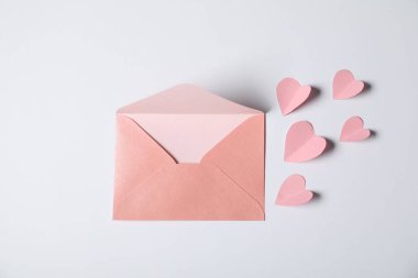 Açık gri arkaplanda bir sürü kağıt kalp ve zarf vardı.