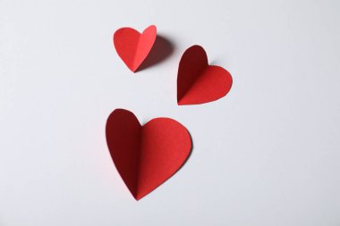 Açık gri arkaplanda kağıt kalpler, yukarıda görünüm