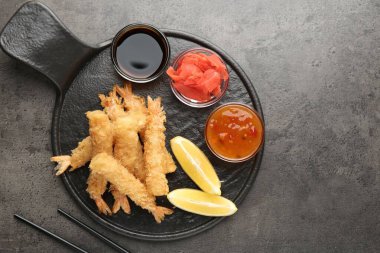 Limon, zencefil ve sosla servis edilen lezzetli tempura karidesleri gri desenli masa, düz yatak. Metin için boşluk