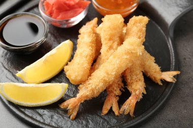Lezzetli tempura karidesleri, limon, zencefil ve soslar gri desenli masada, üst tarafta.