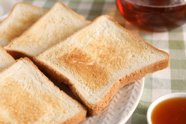 Lezzetli ekmek dilimleri ve kareli masa örtüsü üzerinde reçel, yakın plan.