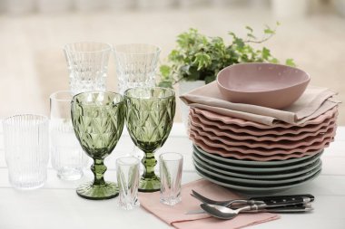 Temiz bardaklar, tabaklar, çatal bıçak takımı ve yeşil saksı.