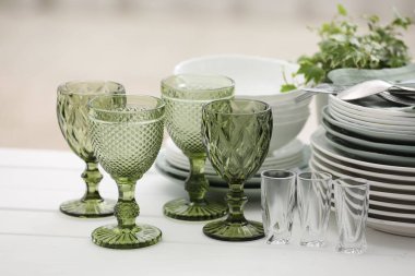 Temiz bardaklar, tabaklar, çatal bıçak takımı ve yeşil saksı.