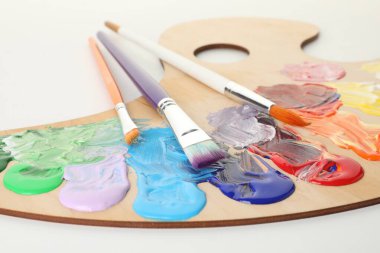 Beyaz arka planda boya ve fırçalı ahşap palet, yakın plan.