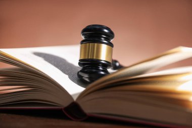 Hakimin tokmağı ve açık kitabı soluk kahverengi arka plana karşı, yakın plan.