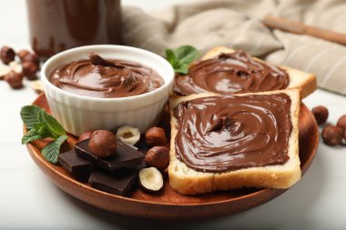 Çikolatalı fındıklı tostlar, fındıklar, çikolata parçaları ve nane şekeri beyaz masada, yakın plan.