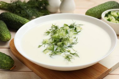 Lezzetli salatalık çorbası ve hafif ahşap masa malzemeleri, yakın plan.