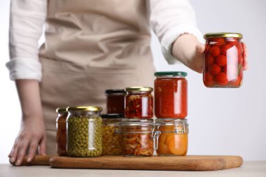 Farklı turşulu ürünlerle dolu kavanozları olan kadın arka planda ışığa karşı, yakın plan.