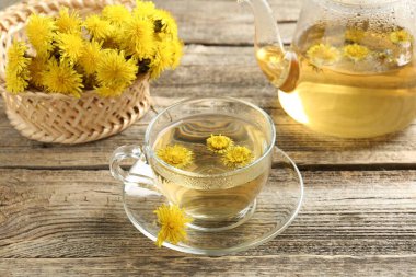 Tazeleyici karahindiba çayı ve çiçekler ahşap masada, yakın plan