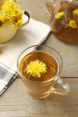 Tahta masada taze karahindiba çayı ve çiçekler.